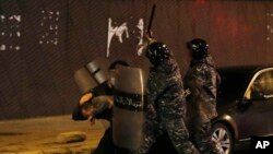 Riot police officers beat an anti-government protester during a protest near the parliament square in downtown Beirut, Lebanon, Dec. 14, 2019.
