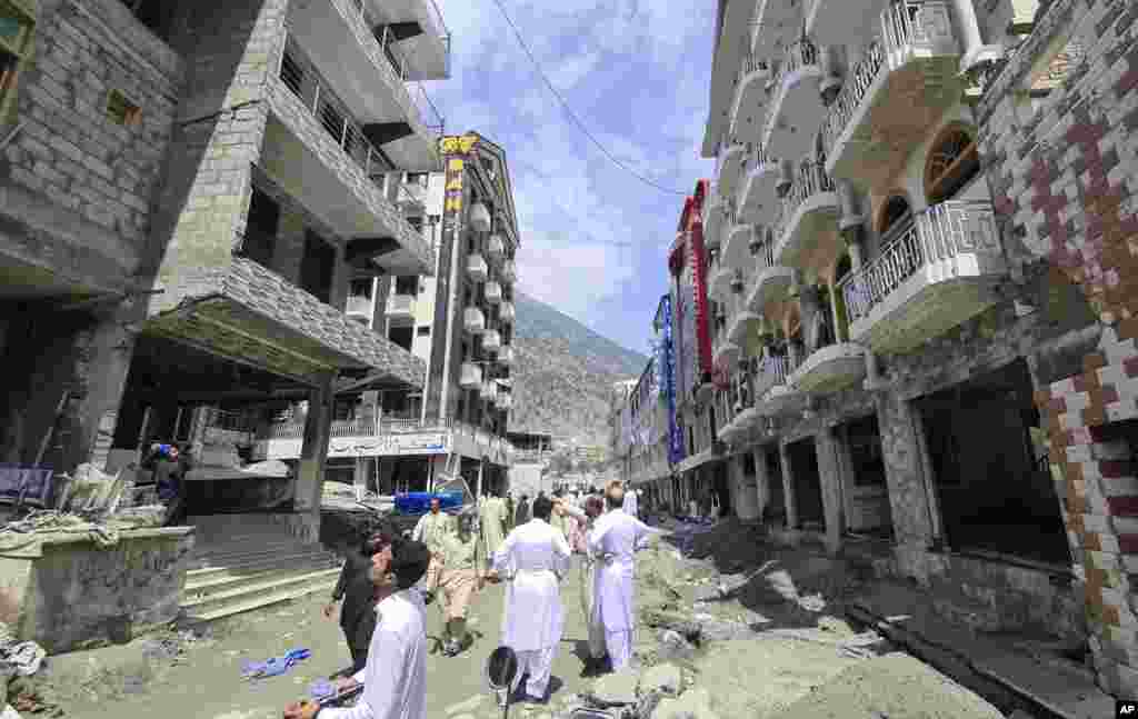 Local residents stand near to the damaged buildings destroyed by floodwaters in Kalam Valley in northern Pakistan, Sept. 4, 2022.