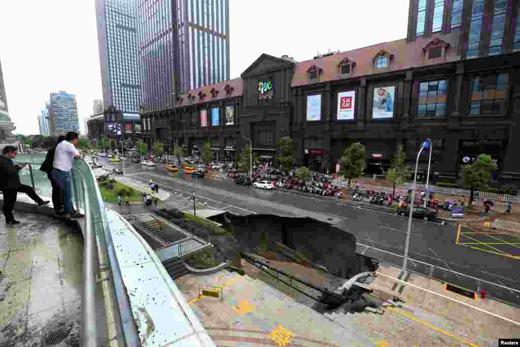 2017年6月10日,在中国江苏省南通市,人们看看塌陷的道路。路面因工地渗水而坍塌,有汽车掉下去。27日,南通市政府通报,道路塌陷事故原因查明,主要为地下径流所致,此外,地表下脱空的形成与基坑回填土不密实有一定关系。