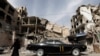 A woman walks past a vehicle parked near damaged buildings in Douma, in the eastern suburbs of Damascus, March 9, 2021. (Omar Sanadiki /Reuters) 