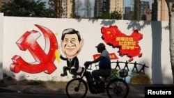 资料照：一名男子骑车路过北京街头一面印有习近平画像的宣传画。（2018年9月28日）
