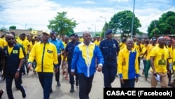 Ao centro, presidente da CASA-CE, Manuel Fernandes, caminha pelas ruas bo bairro Rocha Pinto, em Luanda, num evento da coligação que dirige.