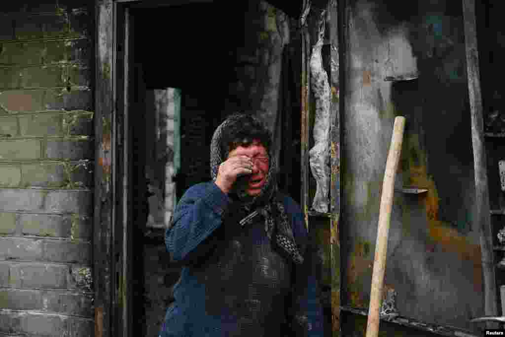 Resident Natalia reacts next to her house heavily damaged during a Russian military strike in the village of Hirske, amid Russia's attack on Ukraine, near the Russian border in Chernihiv region.