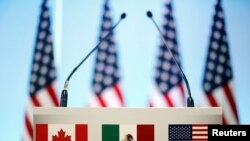 FILE - The flags of Canada, Mexico and the U.S. are seen on a lectern before a joint news conference on the closing of the seventh round of NAFTA talks in Mexico City, Mexico, March 5, 2018. 