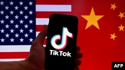 Illustration taken on March 16, 2023 shows the TikTok logo displayed on the screen of an iPhone in front of a US and Chinese flag in Washington, DC. 