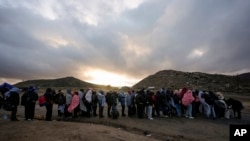 Migrantes que buscan asilo hacen fila en un campamento improvisado para ser procesados después de cruzar la frontera con México, el 2 de febrero de 2024, cerca de Jacumba Hot Springs, California, EEUU.