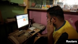 FILE - A man scans social media at an internet club in Islamabad.