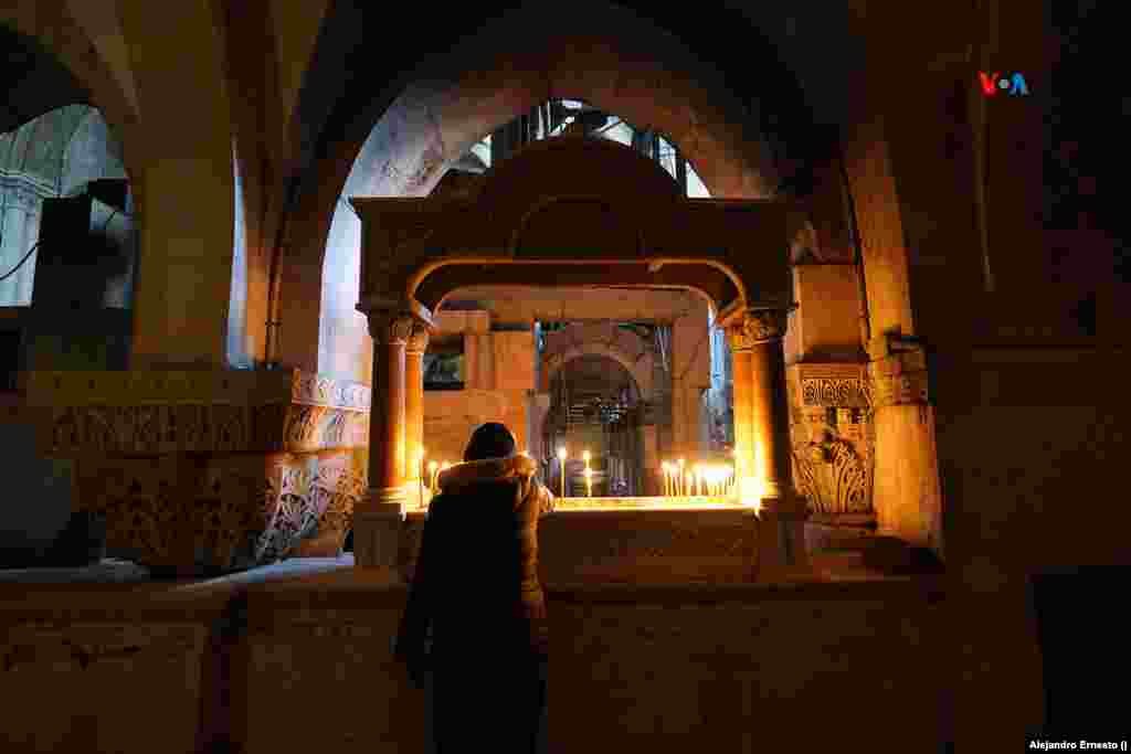 Una mujer enciende una vela en el Calvario, en el interior del Santo Sepulcro de Jerusalén, donde hoy no llegan turistas ni peregrinos.