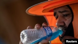 A construction worker drinks a cold beverage during a heat wave in which temperatures have risen over 110 degrees Fahrenheit for 27 consecutive days, in Scottsdale, Ariz., July 28, 2023. 