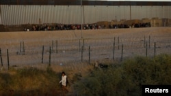 Un migrante que busca asilo en los Estados Unidos pasa por una valla de alambre de púas desplegada para inhibir el cruce de migrantes a los Estados Unidos, vista desde Ciudad Juárez, México, el 28 de noviembre de 2023.