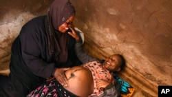 ARCHIVO - Una partera tradicional atiende a una mujer embarazada en su casa, en Simika Village, Chiradzulu, sur de Malawi, el 23 de mayo de 2021.