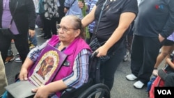 Una devota al Señor de los Milagros asiste portando una imagen a la procesión celebrada en Washington D.C.