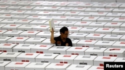 Seorang pekerja membawa bahan pemilihan saat menyiapkan kotak suara sebelum didistribusikan ke TPS di sebuah gudang di Jakarta, 15 April 2019. (Foto: REUTERS/Willy Kurniawan)