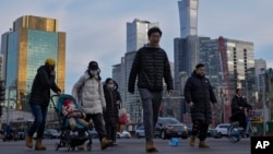 资料照片：行人穿过北京中心商务区办公楼附近的交通路口。（2024年2月8日）