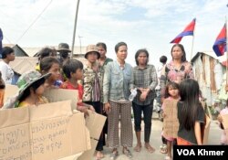 ពលរដ្ឋរស់នៅក្នុងសង្កាត់សំរោងត្បូងជាប់ផ្ទៃបឹងតាមោក ឈរតវ៉ាលើកបដានៅមុខផ្លូវទំនប់កប់ស្រូវនាពីថ្ងៃទី២៧ ខែកុម្ភៈ ឆ្នាំ២០២៤។ (ស៊ឹម ចាន់សំណាង/វីអូអេ)