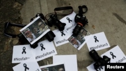 ARCHIVO - Fotógrafos colombianos dejan las cámaras en el suelo frente a la embajada de Ecuador para protestar contra el asesinato de 3 periodistas en Bogotá, Colombia, el 16 de abril de 2018. 