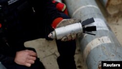 FILE - A member of the Ukrainian military holds a defused cluster bomb among a display of pieces of Russian army rockets that a Ukrainian munitions expert said did not explode on impact, in Kharkiv region, Ukraine, Oct. 21, 2022. 
