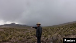 Un hombre señala una nube de ceniza del volcán Ubinas, en Santiago de Machaca, Bolivia, a lo largo de la frontera con Perú, el 20 de julio de 2019.