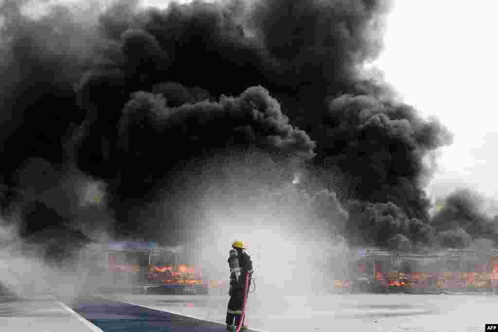 A firefighter sprays water to control the burning of seized illegal drugs during a destruction ceremony to mark the U.N.'s "International Day against Drug Abuse and Illicit Trafficking" in Yangon, Myanmar.