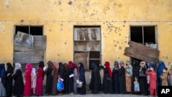 FILE - Afghan women wait to receive food rations distributed by a humanitarian aid group, in Kabul, Afghanistan, May 28, 2023.