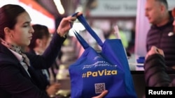 Stjuardesa sa torbom na kojoj stoji natpis #BezViza na prištinskom aerodromu (Foto: REUTERS/Laura Hasani)