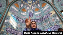An Iranian woman gestures at a polling station in a snap presidential election to choose a successor to Ebrahim Raisi following his death in a helicopter crash, in Tehran, Iran, June 28, 2024. (West Asia News Agency via Reuters)