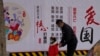 一名男子带着小女孩走过北京街头一面中国政府的宣传社会主义核心价值观的宣传墙。（2021年3月7日）