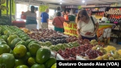 ARCHIVO - Una cliente observa uvas y fresas en un negocio de comida en Maracaibo, en el occidente de Venezuela, en julio de 2023.