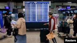 Orang-orang melihat informasi penerbangan di Bandara Internasional Taoyuan, Taiwan, 12 April 2023.