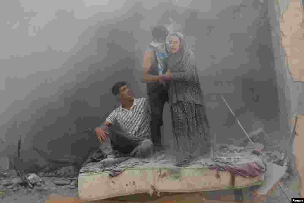 Palestinians react at the site of an Israeli strike on a house, amid the Israel-Hamas conflict, in Deir Al-Balah, in the central Gaza Strip.