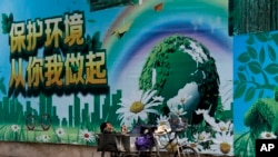 资料照：一名工人在北京的一面"保护环境从你我做起"的宣传画前休息。（2017年6月5日）