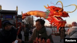 北京一個公園慶祝龍年的裝飾前一名女子在買糖葫蘆。 (2024年2月7日)