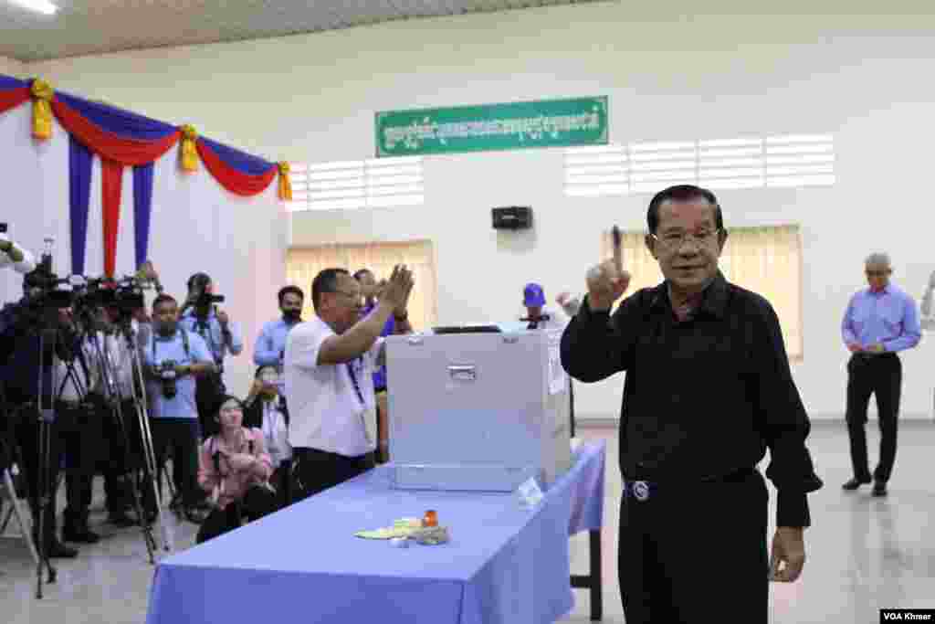 លោក ហ៊ុន សែន ប្រធានគណបក្សប្រជាជនកម្ពុជា លើកដៃចង្អុលបង្ហាញអ្នកសារព័ត៌មាន បន្ទាប់ពីដាក់សន្លឹកឆ្នោតចូលធុង នៅក្នុងមណ្ឌលបោះឆ្នោតខេត្តកណ្តាល កាលពីថ្ងៃទី២៥ ខែកុម្ភៈ ឆ្នាំ២០២៤។ (លាស់ លីបលីប/វីអូអេ)