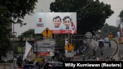 Masyarakat berjalan melewati baliho Menteri Pertahanan dan calon Presiden Prabowo Subianto dan pasangannya Gibran Rakabuming Raka di Jakarta, 12 Januari 2024. (Foto: REUTERS/Willy Kurniawan)