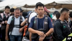 ARCHIVO - Migrantes hacen fila para abordar un bote para cruzar el Golfo de Urabá y comenzar su caminata a través del Tapón del Darién en su camino a Estados Unidos en Necoclí, Colombia, el sábado 7 de octubre de 2023. (Foto AP/Ivan Valencia)