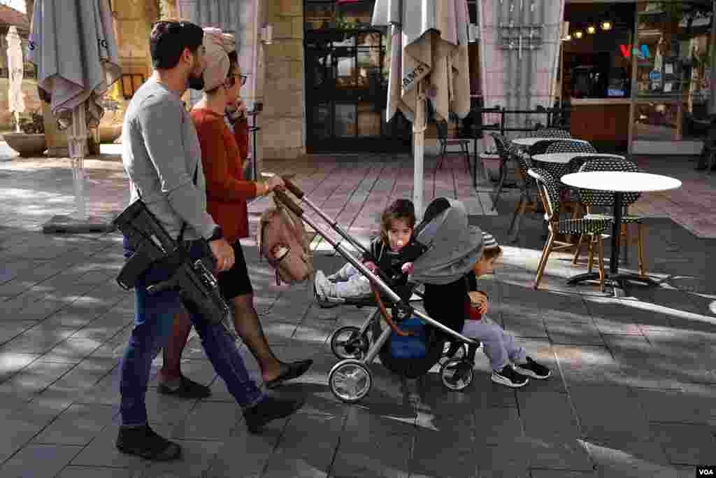 Un hombre armado con un rifle de asalto pasea con su familia por el centro de Jerusalén.