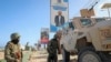 Des soldats de la paix ougandais de la Mission africaine de transition en Somalie (ATMIS) se tiennent à côté de leur véhicule blindé dans une rue de Mogadiscio, en Somalie, le 10 mai 2022.