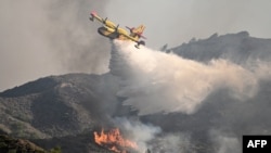 Sebuah pesawat pemadam kebakaran menjatuhkan air di atas api yang membakar dekat desa Vati di bagian selatan pulau Rhodes, Yunani, sekitar 70 kilometer barat daya ibu kota, 25 Juli 2023.