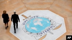 FILE - People walk on the Interpol logo at the international police agency headquarters in Lyon, central France, Nov. 8, 2018. 