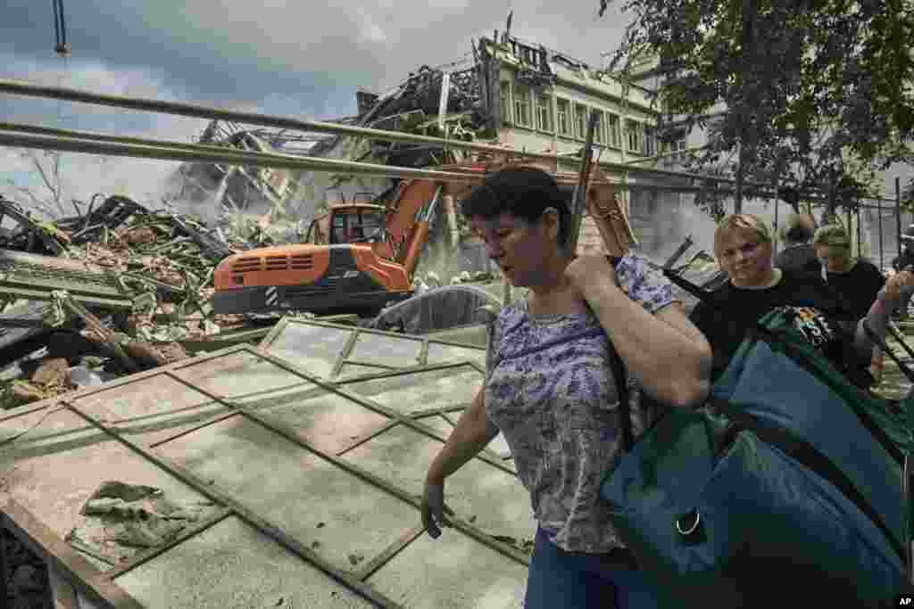 La gente carga con sus pertenencias mientras el personal del servicio de emergencia trabaja en el sitio de edificios destruidos en el centro de la ciudad patrimonial de Odesa, después de un ataque ruso el jueves 20 de julio de 2023. 