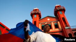 Una mujer haitiana que sostiene la bandera nacional del país en su espalda asiste a la inauguración del reconstruido mercado de hierro Hyppolite en Puerto Príncipe, el 11 de enero de 2011.