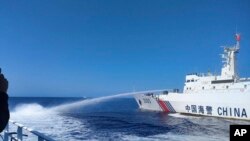 Dalam foto dari Garda Pantai Filipina tampak kapal Garda Pantai China (kanan) menggunakan meriam air ke kapal Filipina saat berlayar mendekati laguna Scarborough Shoal di Laut China Selatan yang disengketakan, Sabtu, 9 Desember 2023. (Foto: Garda Pantai Filipina via AP)