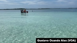 Un vendedor de comida camina en el mar en busca de clientes que pasan tiempo en el cayo conocido como Bajo 360 en el estado Falcón, en el occidente de Venezuela, el viernes 25 de agosto de 2023.
