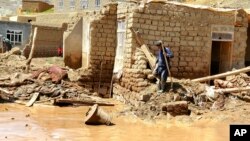 An Afghan man collects his belongings from his damaged home after heavy flooding in Ghor province in western Afghanistan, May 18, 2024.