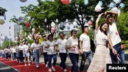 ຄູ່​ຮັກຫຼາຍ​ຄູ່​ເຂົ້າ​ຮ່ວມ​ພິ​ທີ​ແຕ່ງ​ງານ​ຮ່ວມ​ກັນ​ໃນ​ເມືອງ ຣູ​ກາວ, ແຂວງ ຈຽງ​ຊູ, ຈີນ, 20 ພຶດ​ສະ​ພາ 2020.