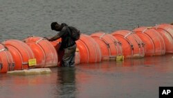 Migrant iz Kolumbije stoi na plutajućim bovama dok pokušava da pređe Rio Grande iz Meksika u SAD, kod Igl Pasa, Teksas, 21. avgusta 2023.