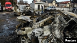 A man walks next to cars destroyed in a Russian missile and drone attack, in Kyiv, Ukraine, Dec. 29, 2023.