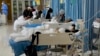 FILE - People attend to relatives receiving medical treatment at a hospital in Beijing, Jan. 7, 2023. Rising premiums and reduced benefits are two of the factors behind a drop in the number of Chinese enrolled in the basic government-run health plan.