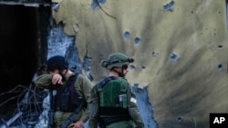 Soldados israelíes pasan junto a casas destruidas por militantes de Hamás en el Kibutz Be'eri, Israel, el sábado 14 de octubre de 2023. El kibutz fue invadido por militantes de Hamás de la cercana Franja de Gaza en octubre 7 cuando mataron y capturaron a muchos israelíes.