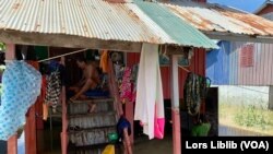 លោក ហ៊ន ហ៊ុន រស់នៅ​ភូមិពាម សង្កាត់​ព្រៃស ខណ្ឌដង្កោ រាជធានីភ្នំពេញ កំពុង​អង្គុយ​លើ​ផ្ទះ​ឈើ បេះបន្លែ ខណៈ​ភរិយា​របស់​លោក កំពុងដើរ​មើល​សម្ភារ​ក្រោមផ្ទះ ស្របពេល​កម្រិត​ទឹក​ចាប់ផ្តើម​ស្រកចុះ។ រូបនេះ ថតនៅ​ថ្ងៃទី២៣ ខែតុលា ឆ្នាំ២០២៣។ (លាស់ លីបលីប/វីអូអេ)
